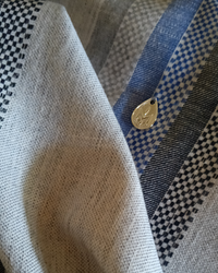 Close-up of a fabric with a the white bronze silver-plated Natalie Noor tag.