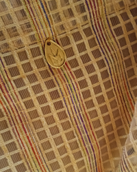 Close-up of a patterned fabric with a Natalie Noor logo engraved in nordic gold tag.