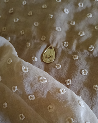Gold pendant with Natalie Noor Crown, on nude uragiri chiffon fabric.