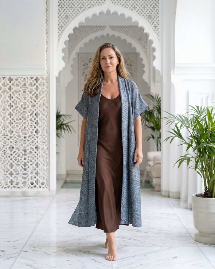 Natalie Noor wearing the moonstone blue Mirage robe with intricate metallic black and gold embroidery. A Luxury Sahara Resort Wear collection.