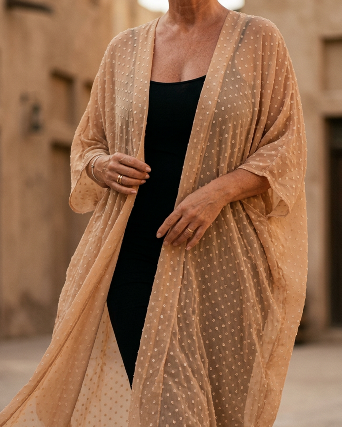 Natalie Noor wearing a nude uragiri chiffon robe, over a black dress in Al Seef, Dubai.