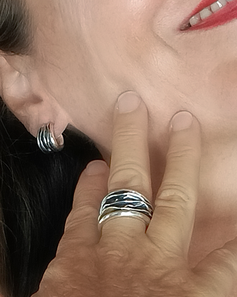 Close-up of a person wearing a silver ring and earrings.