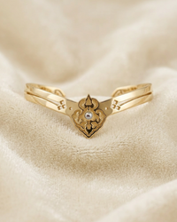Golden cuff bracelet with a decorative clasp on a beige fabric background.