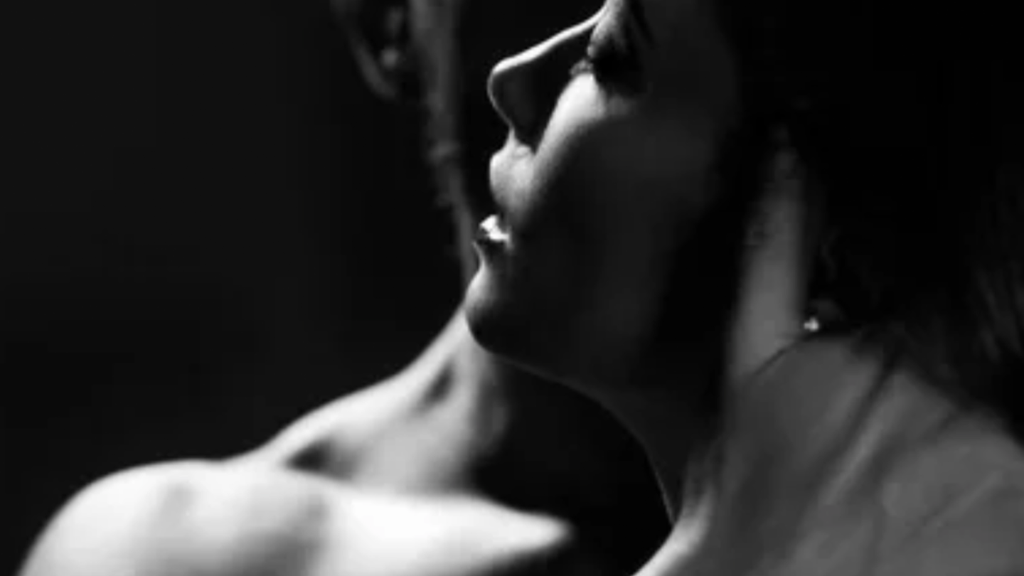 Black and white close-up of a person embracing another, with a dark background. Maison Natalie Noor, memory, legacy, ritual, storytelling. Fragrant Portals.