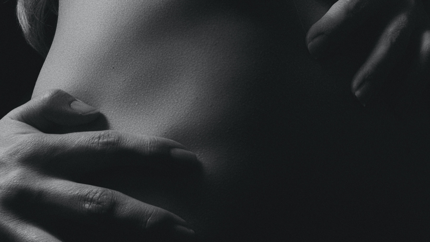 Black and white close-up of a person's hands hugging someone.
