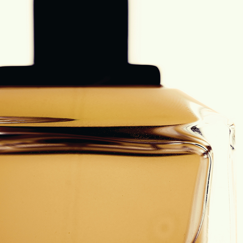 Close-up of a perfume bottle with a black cap on a light background. A Fragrant Portal by Natalie Noor