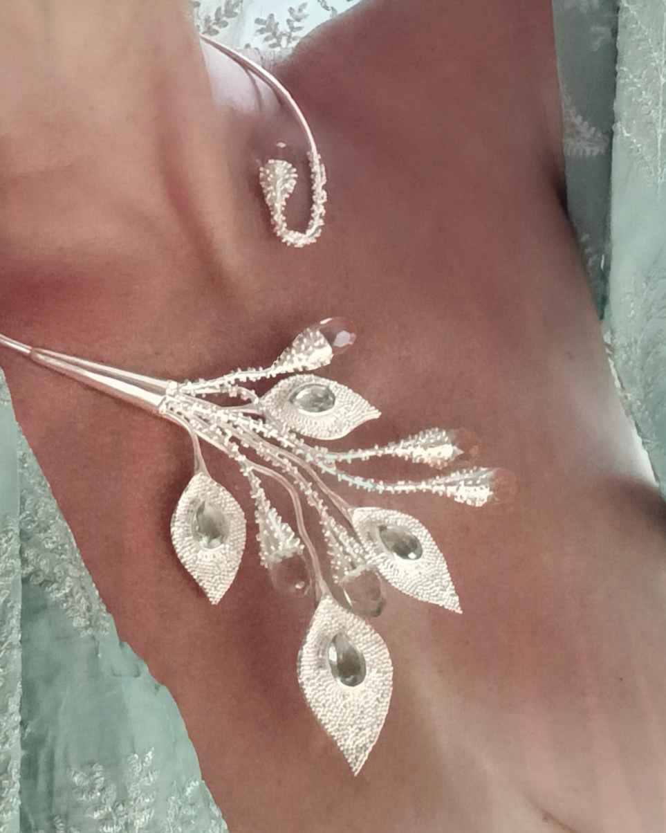 Silver leaf-shaped torc necklace on a chest with a light background. Blue obsidians. Maison Natalie Noor,, jewelry lit by desire.