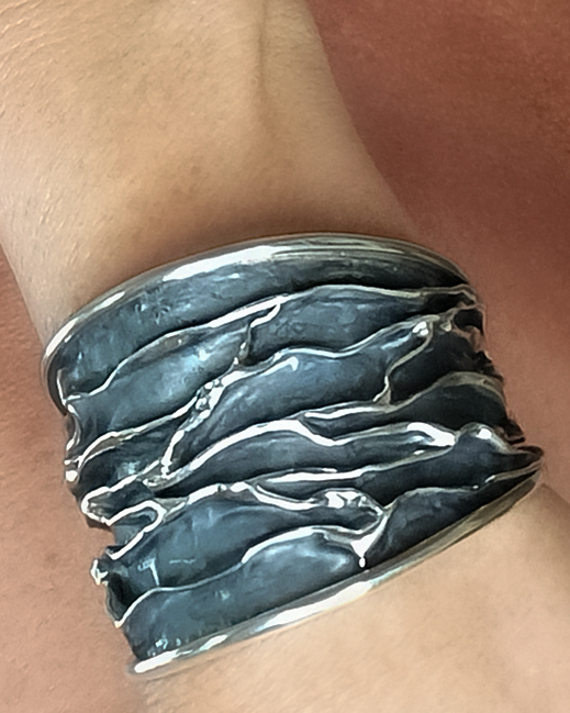 Silver bracelet on a wrist with a naked skin background. Maison Natalie Noor, jewelry lit by desire.