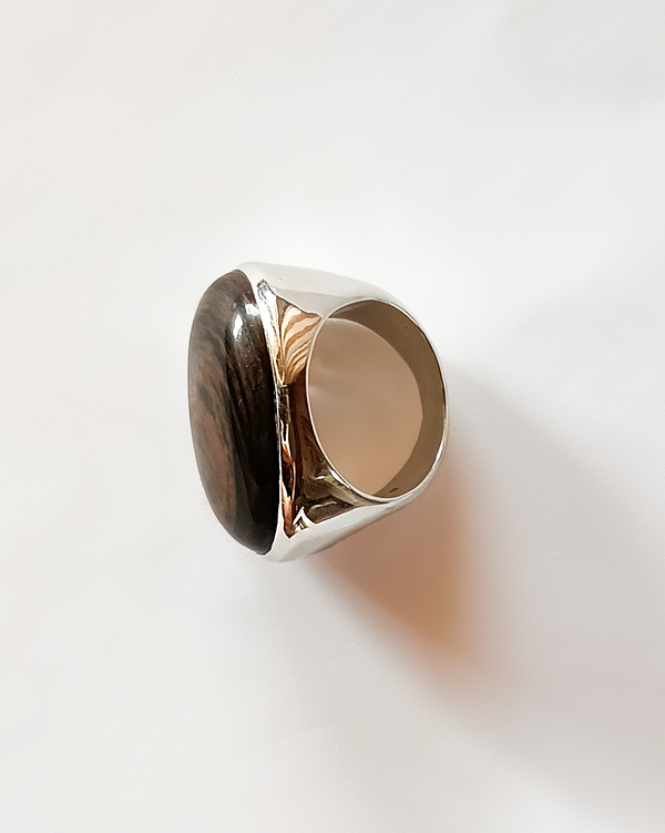 Silver ring with a brown copper obsidian  gemstone on a light gray background. Maison Natalie Noor, Jewelry lit by desire.