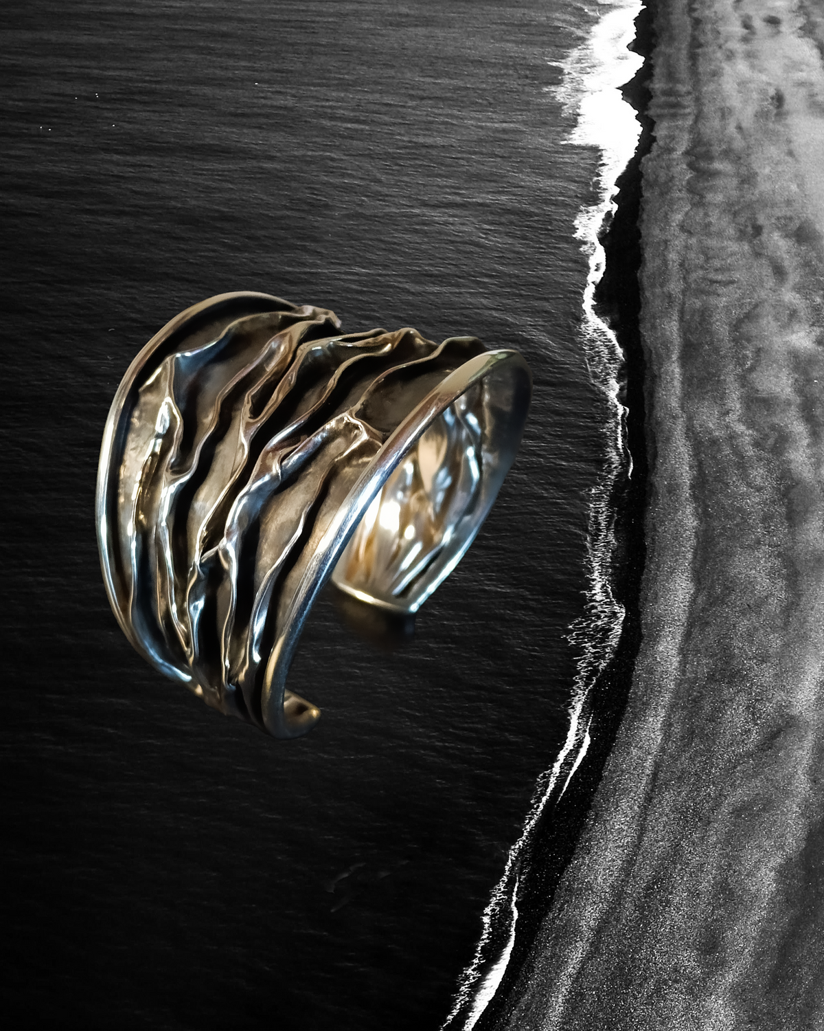 Silver Cuff bracelet with wavy design on a black and white beach background. Maison Natalie Noor, jewelry lit by desire.