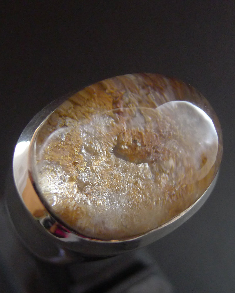 Close-up of a stone with a metallic sheen on a dark background. Lodolite gemstone, garden quartz.