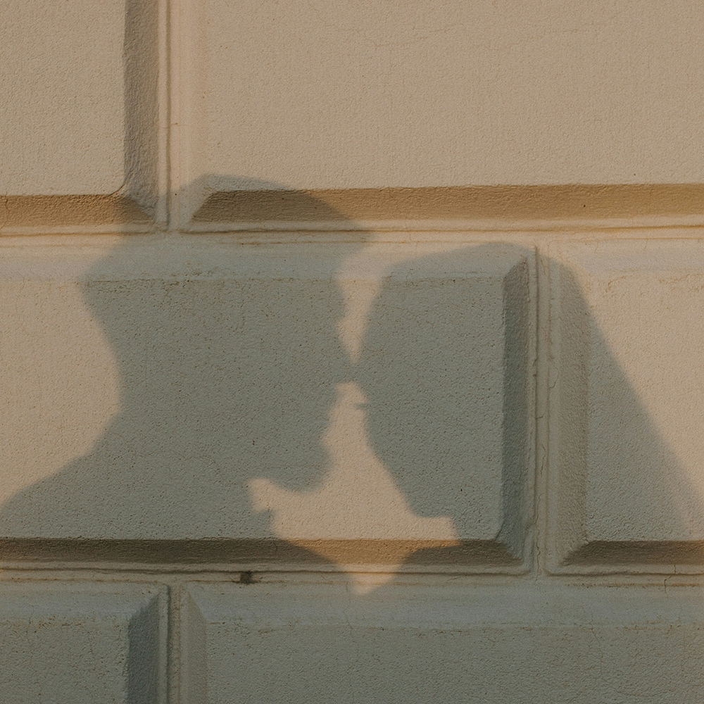 Close-up of a decorative brick pattern on a wall with the shadow of a couple face to face. Maison Natalie Noor
