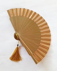 Gold hand fan with a tassel on a white background