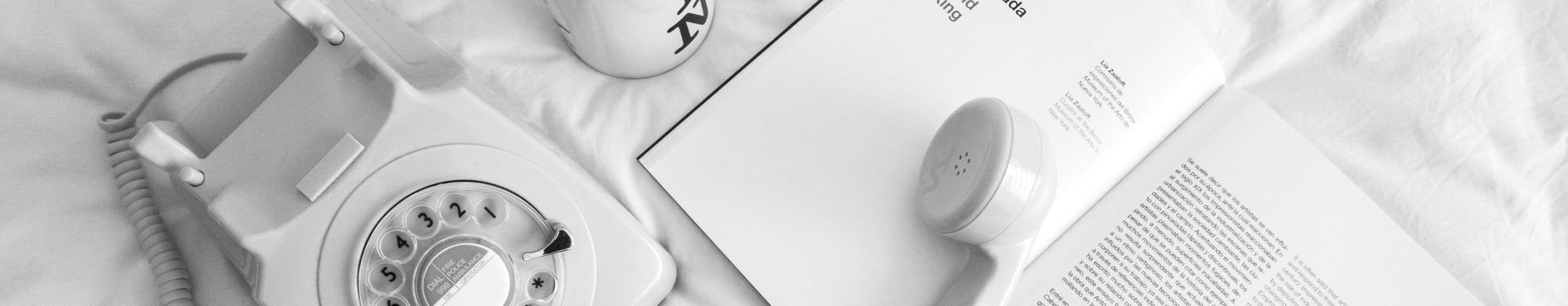 Vintage rotary phone, coffee cup, and newspaper on a white surface