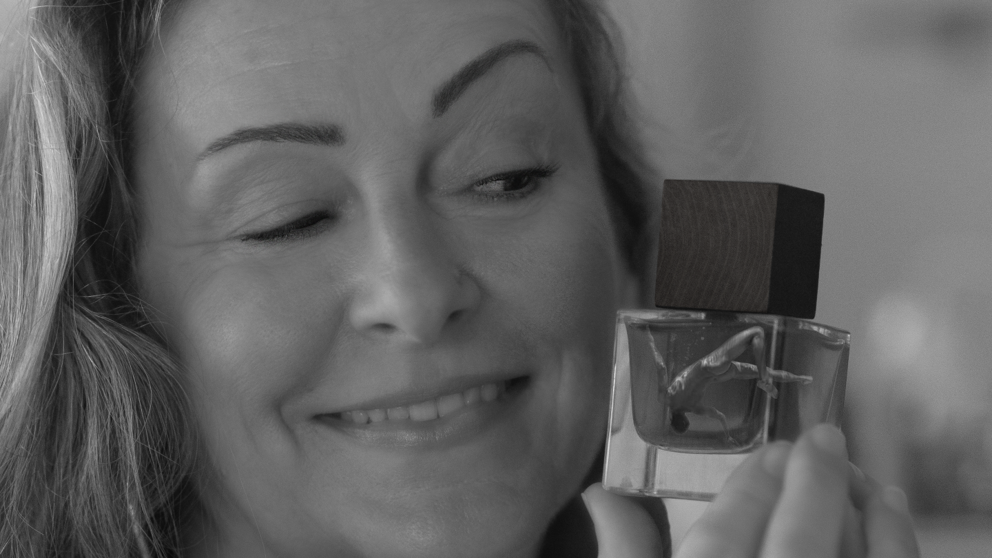 Woman holding a perfume bottle with a blurred background.