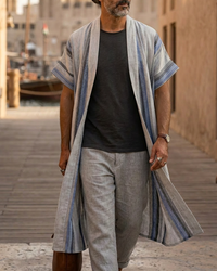 Man wearing a long, light-colored robe with blue stripes in an arabic traditional town. A Sahara Resort Wear Collection by Natalie Noor