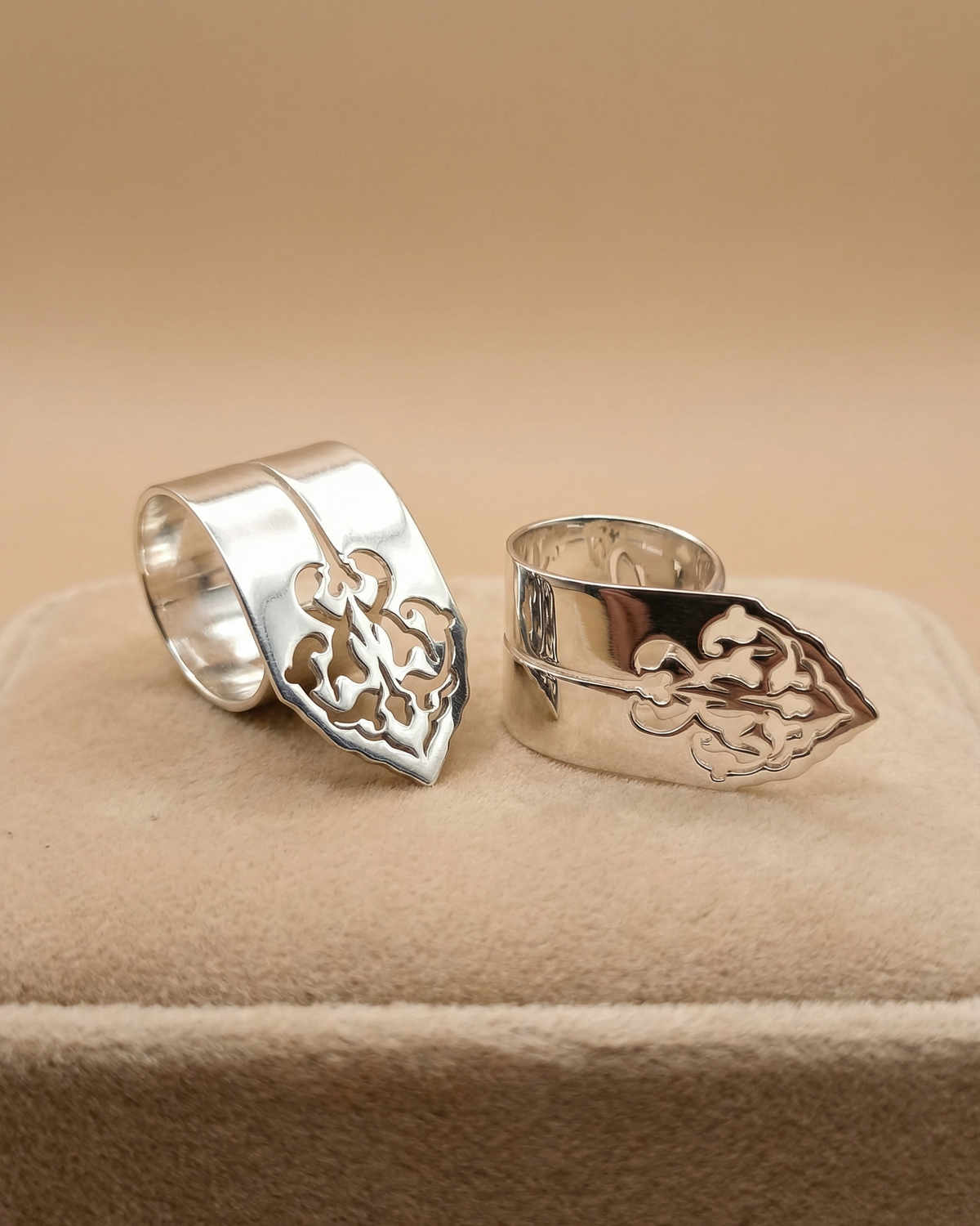 Two silver plated rings from the Sharafeh Collection by Natalie Noor displayed on a soft suede beige fabric. Jewelry lit by Desire.